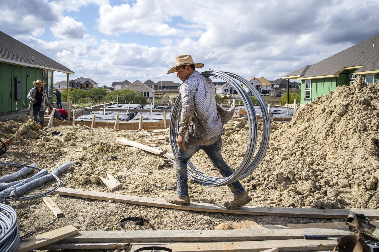 A construction worker carries materials while building a new home in Texas.