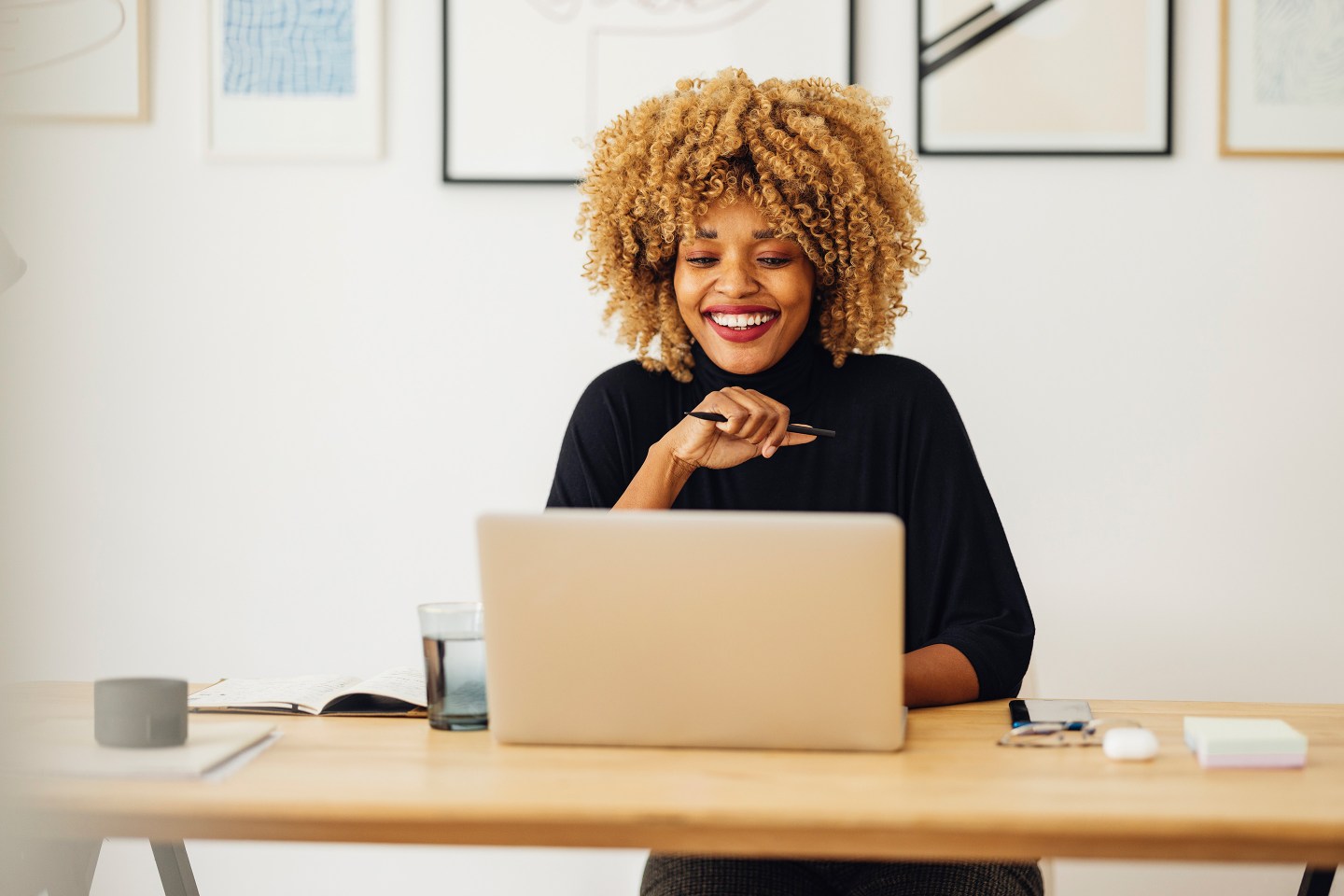 Smiling Woman Sitting in an Office and Looking at a Laptop
