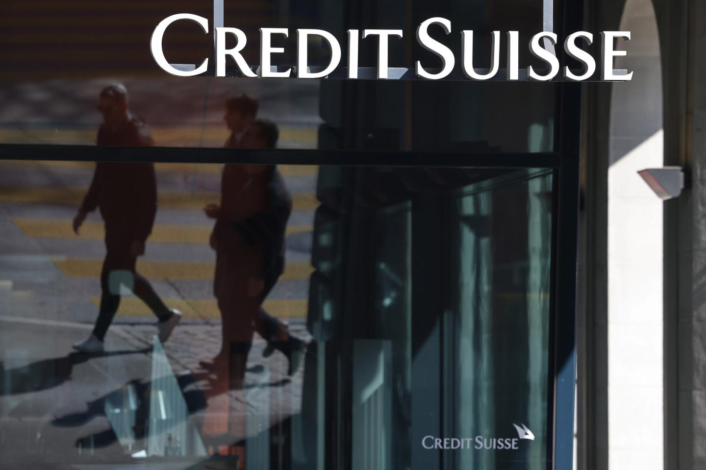 People walking in front of a Credit Suisse office.
