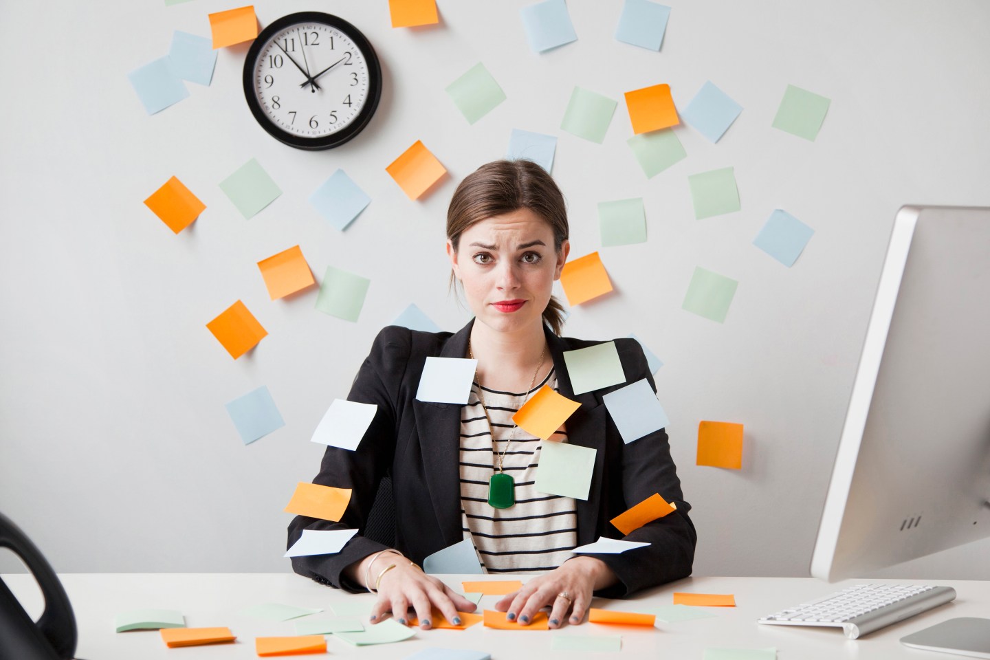a woman at a desk with Post-it notes on her clothes and the wall