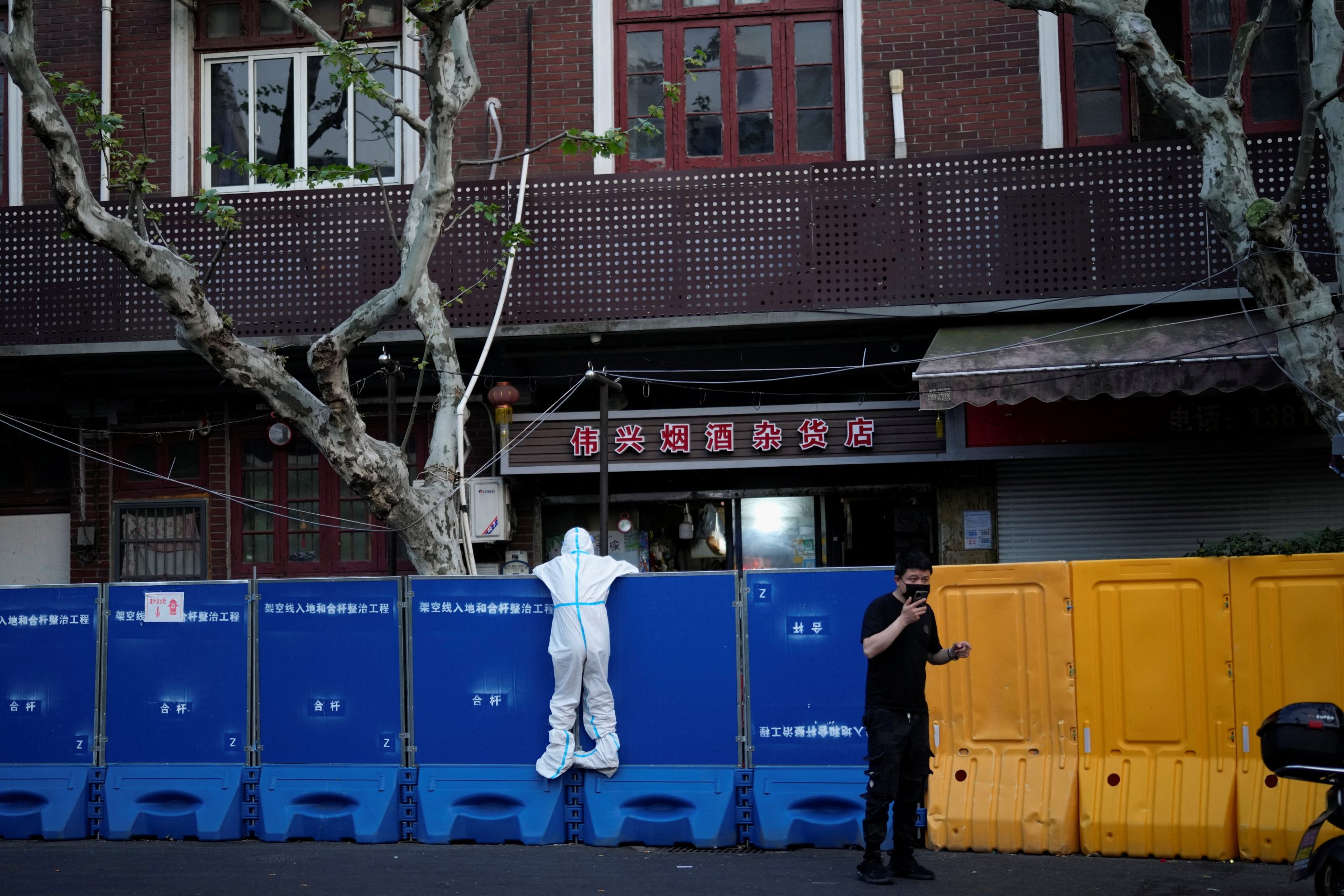 A person in a protective suit looks over barricades set around a sealed-off area, during a lockdown to curb the spread of COVID-19 in Shanghai, April 11.