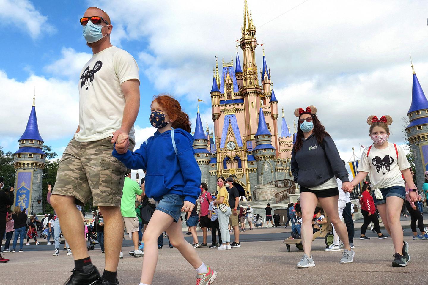 A family walks past Cinderella Castle in the Magic Kingdom at Walt Disney World in Lake Buena Vista, Fla.