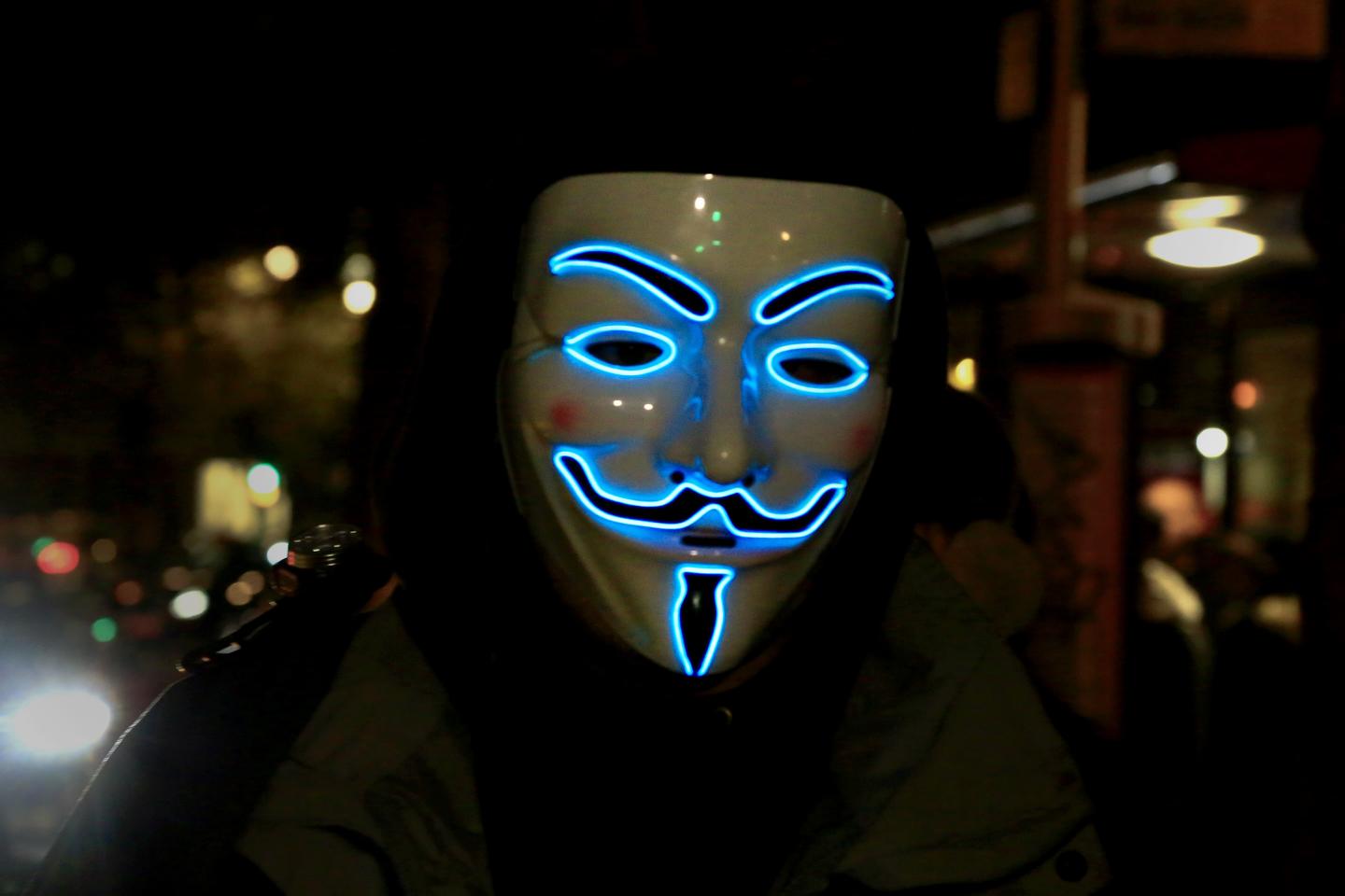 A demonstrator wearing a led Vendetta mask takes part in a protest.