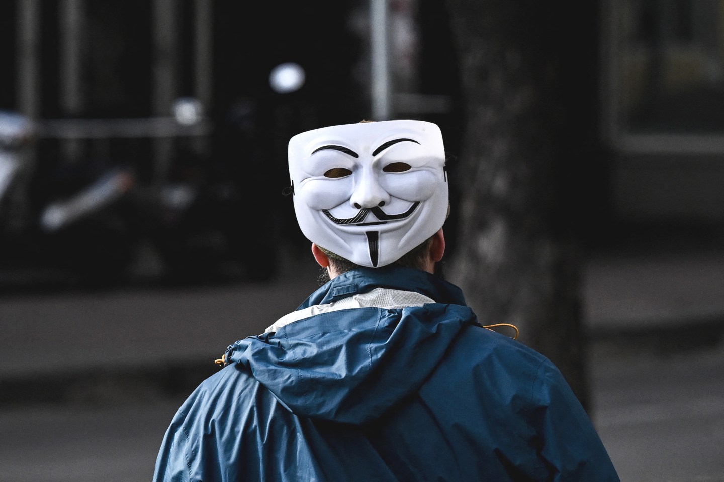 A man wearing Anonymous mask on the back of his head.