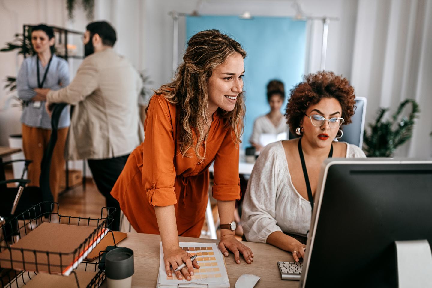 Businesswoman using desktop computer with colleague