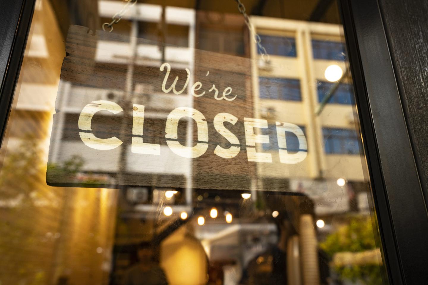 A “closed” sign hanging in a window