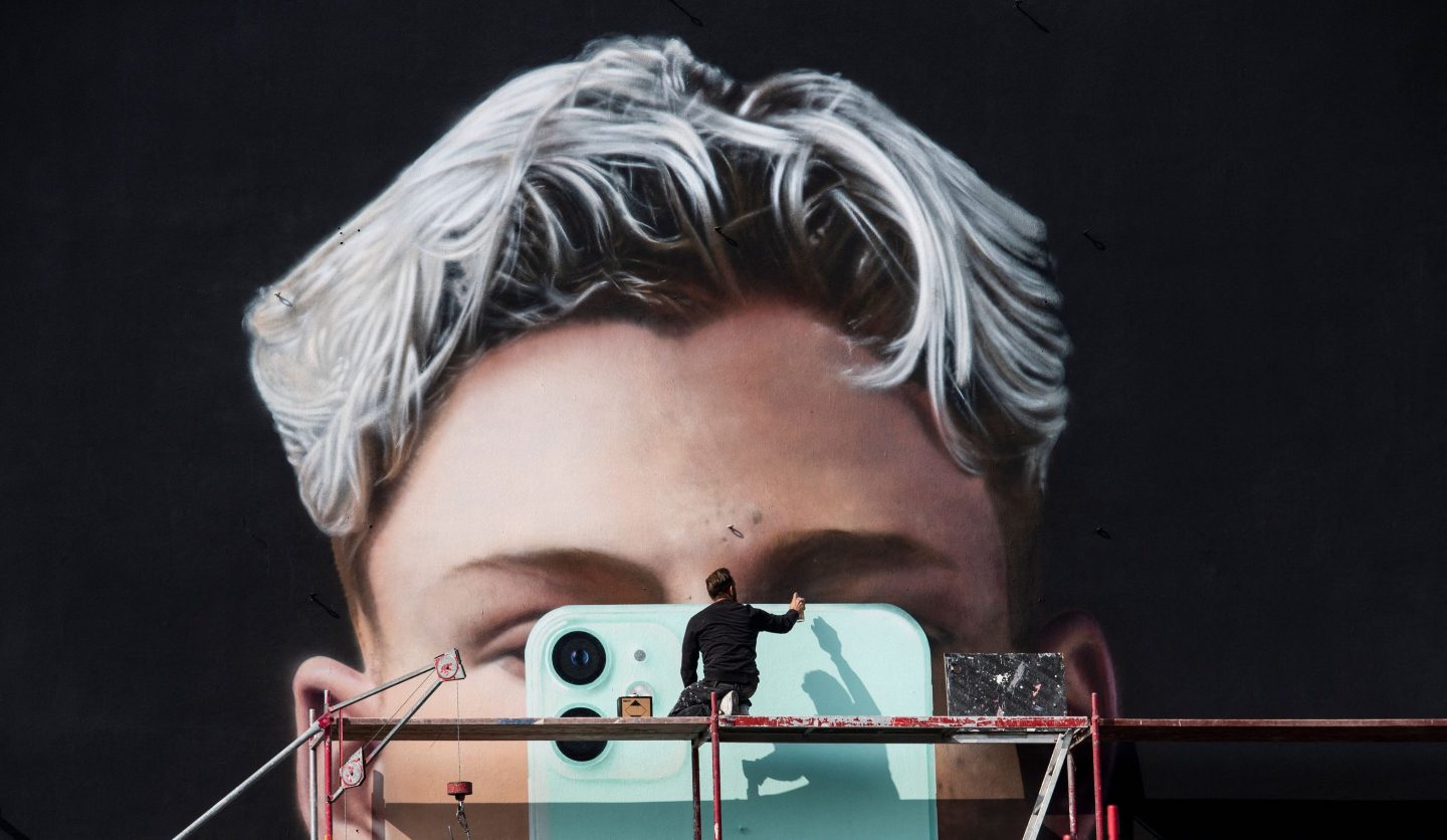 A graphic artist paints a mural ad for Apple in Berlin