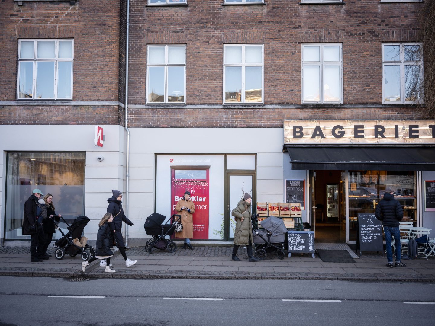Customers stand a social distanced queue outside a bakery in Copenhagen, Denmark