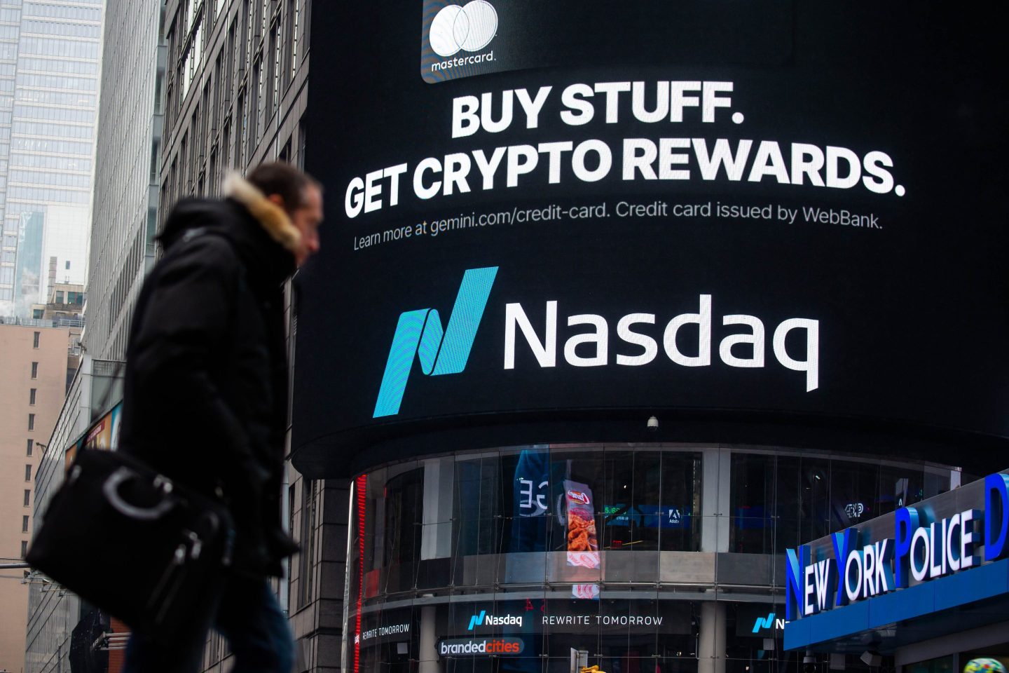 Person walks by Nasdaq in Times Square.
