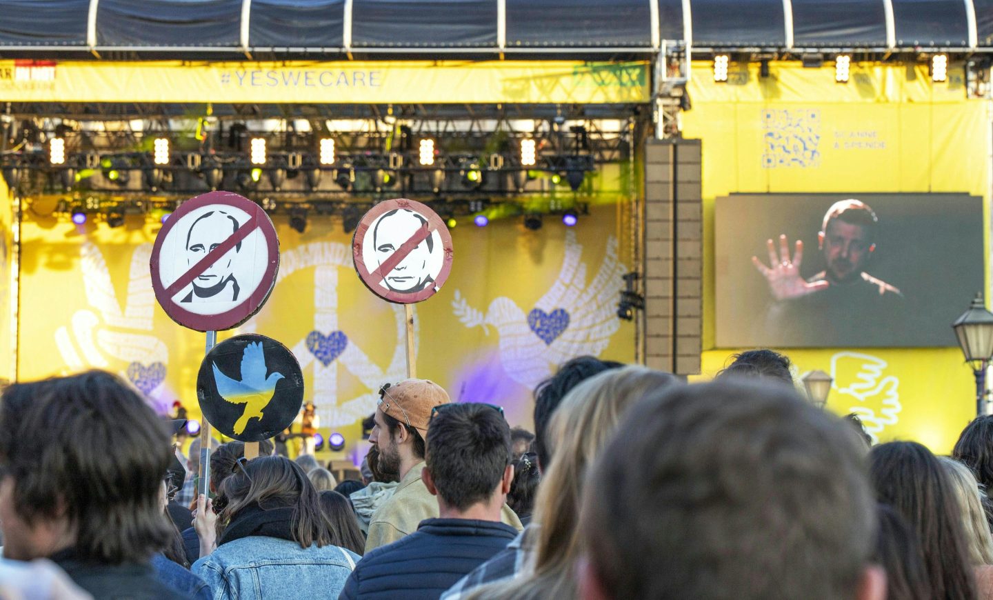 Ukrainian President Volodymyr Zelensky, seen on a video screen, addresses participants at an anti-Putin demonstration in Vienna