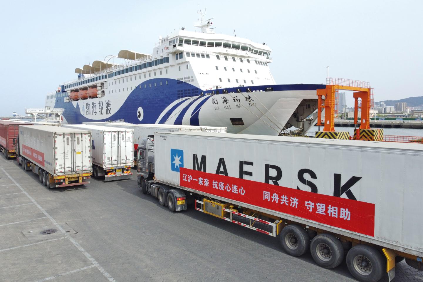 A Maersk truck parked in front of a container ship