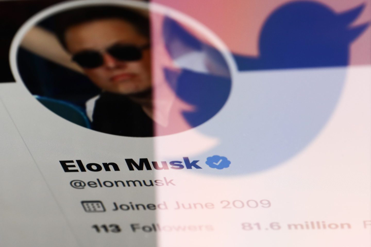 Elon Musk's Twitter profile displayed on a screen and reflected Twitter logo displayed on a phone screen are seen in this illustration photo taken in Krakow, Poland on April 14, 2022.