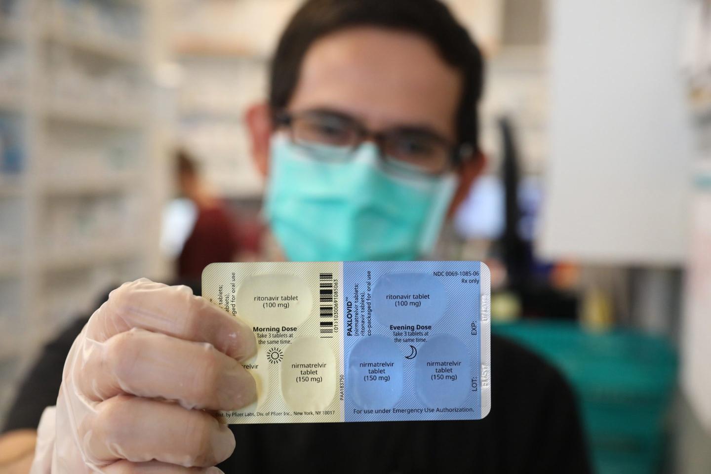 A pharmacy manager in Chicago holds a package of Pfizer Paxlovid pills