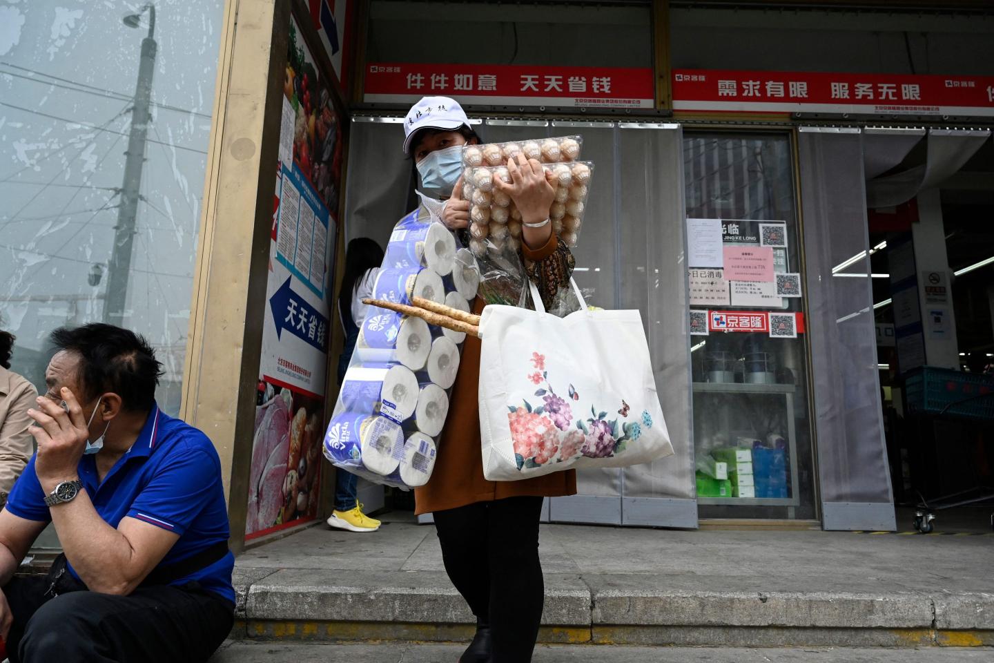 A woman carries eggs and toilet paper leaving a Beijing supermarket
