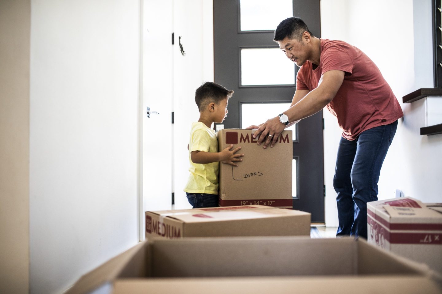 Father and son arrange moving boxes in new home