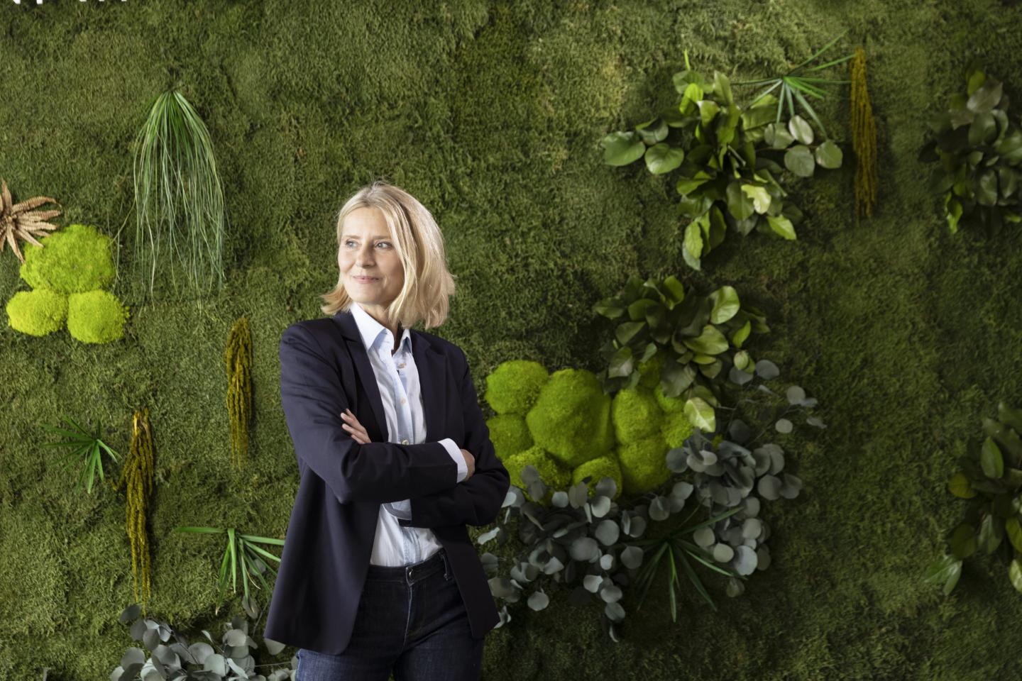 Female professional standing with arms crossed in front of plants