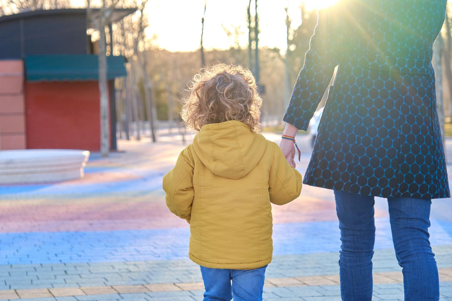 Mother walking hand in hand with her young son to school