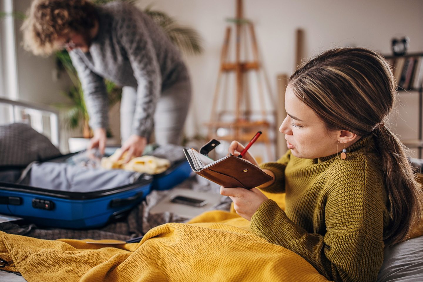 Two people packing suitcase for a trip
