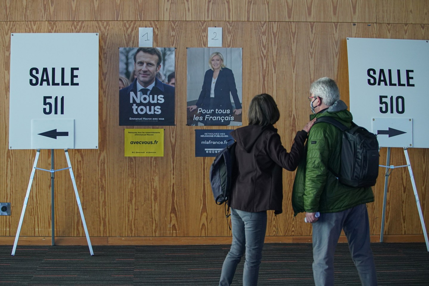French citizen walk by posters of candidates Emmanuel Macron and Marine Le Pen as they go to vote in the second round of France's presidential election at the Palais des Congres on April 23, 2022 in Montreal, Quebec, Canada. Emmanuel Macron and Marine Le Pen both qualified on Sunday, April 10 for France's Presidential Election second round to be held on April 24.