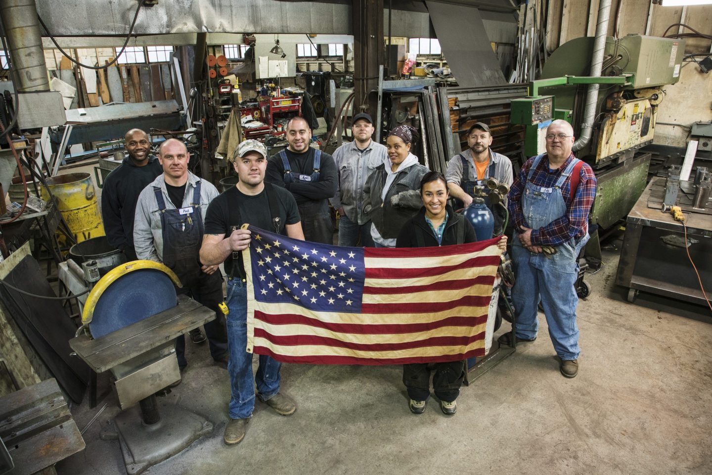 Workers holding American flag in factory