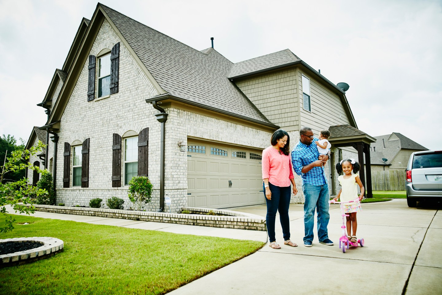 Portrait of family in driveway in front of home.