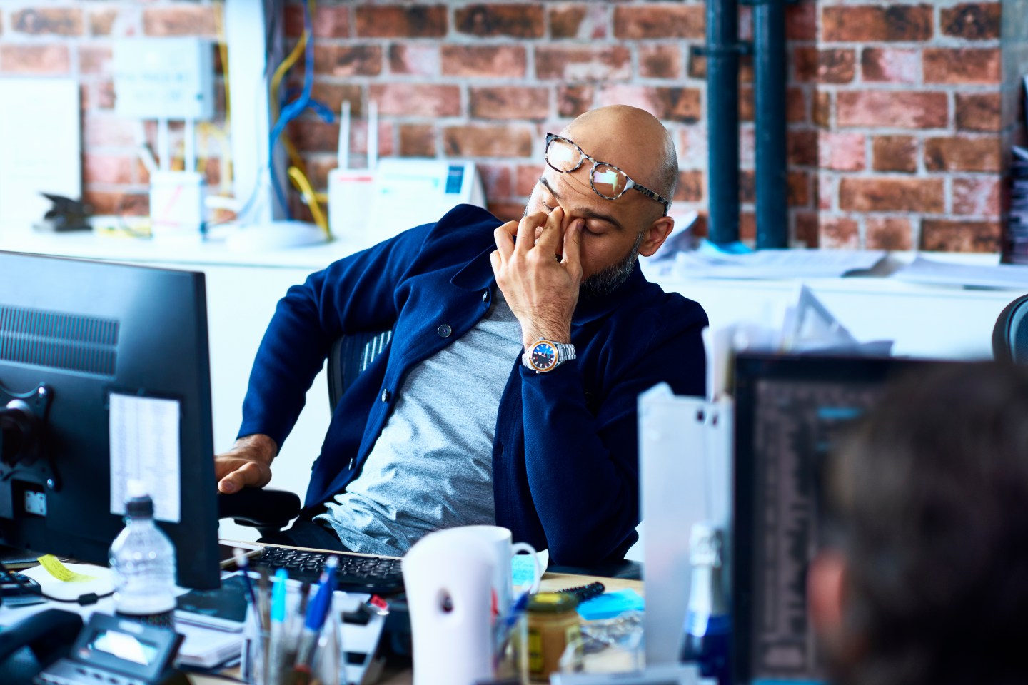 Tired man sitting at desk in modern office