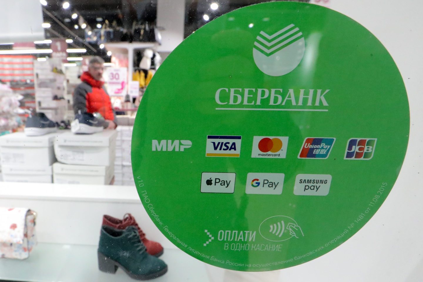 A man shops in a store in front of a logo of various credit card companies accepted in Russia.