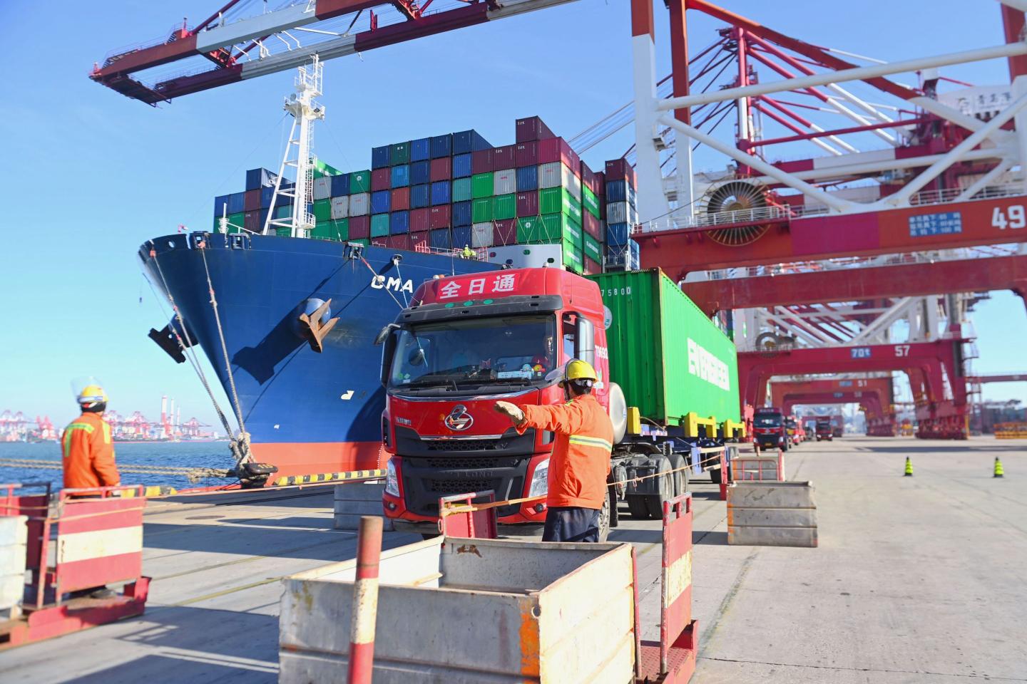 Workers direct a truck at Shanghai's port.