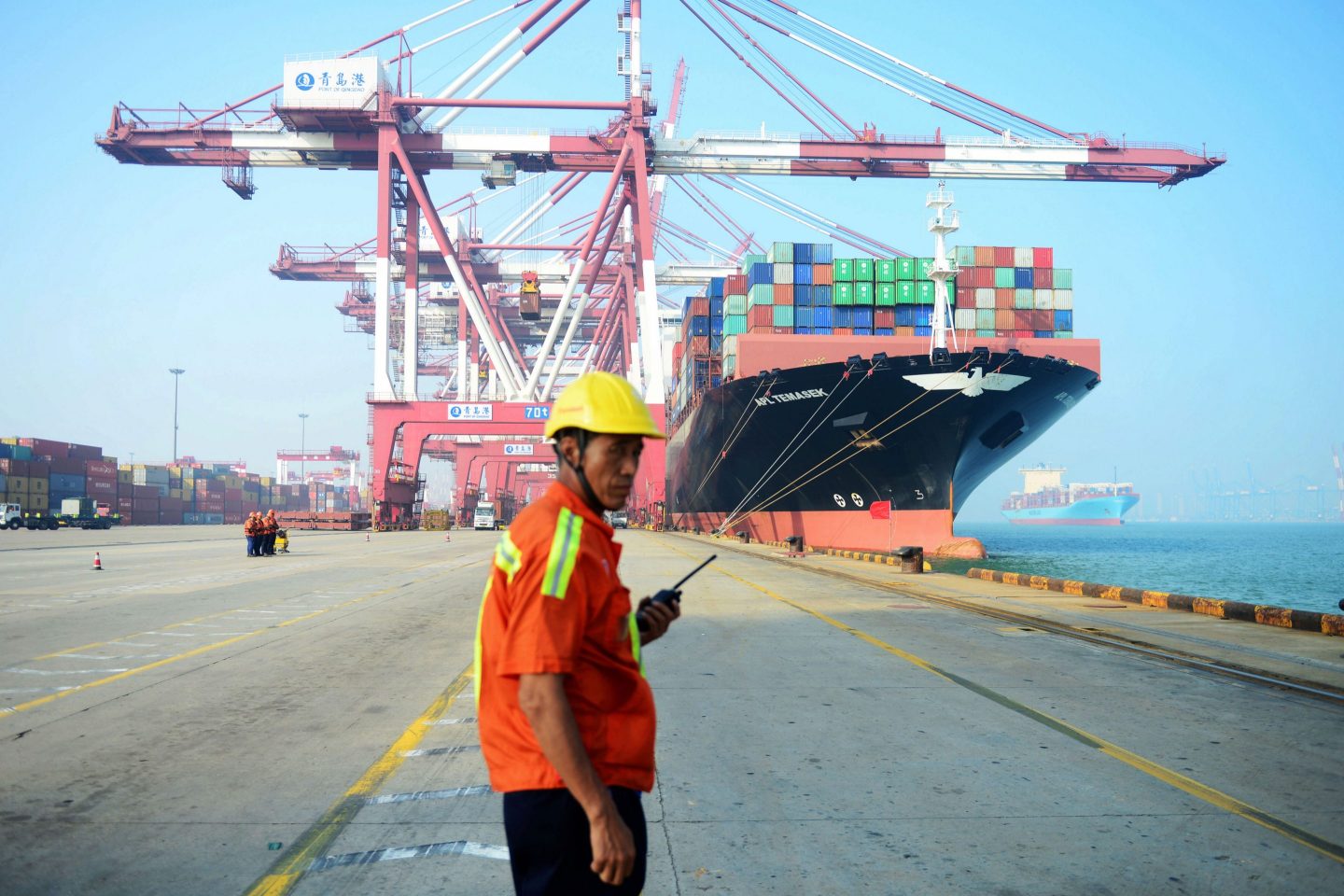 A worker stands holding a two way radio at a Chinese port.