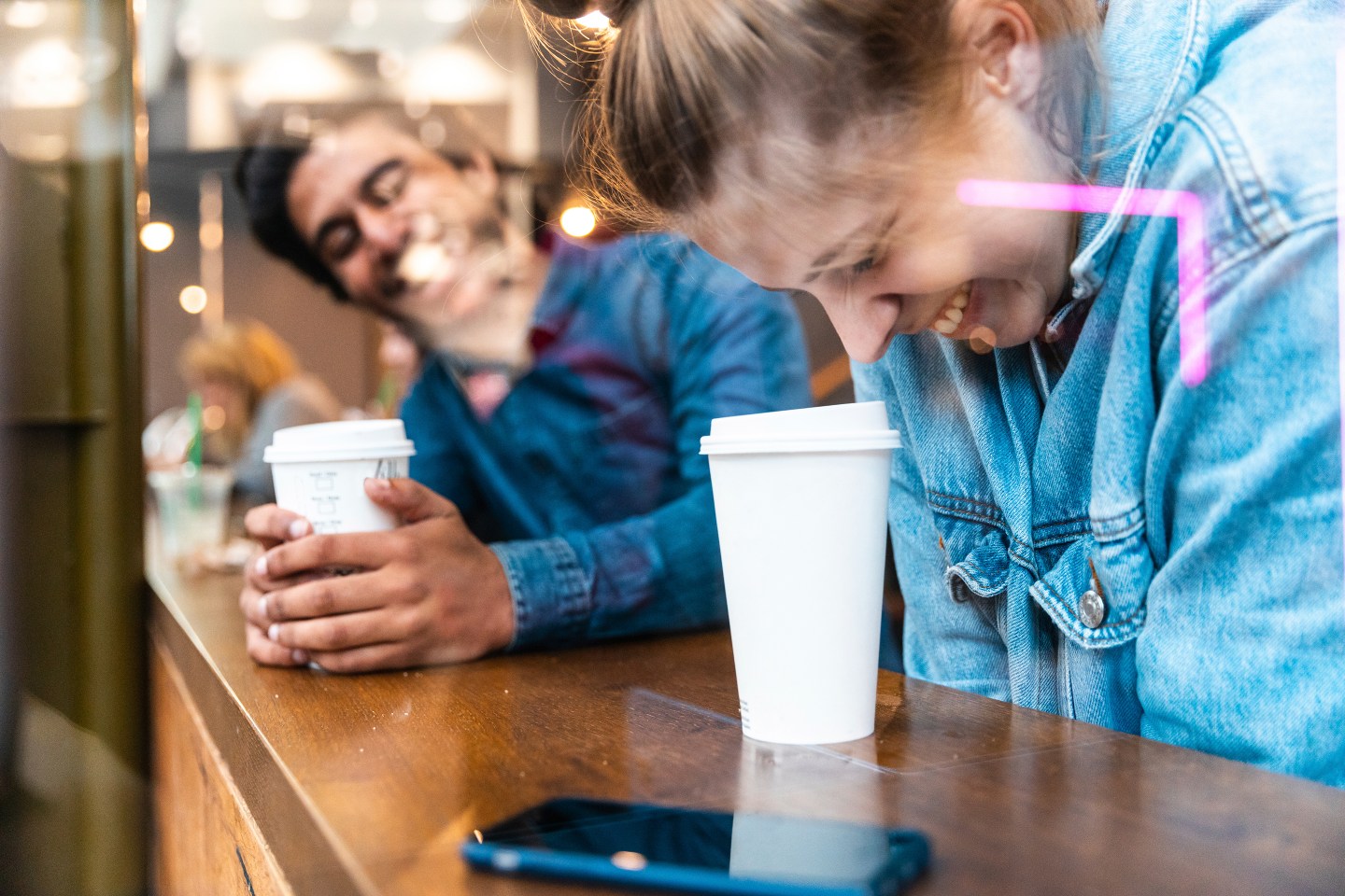 Two young people laugh in a coffee shop on a date.