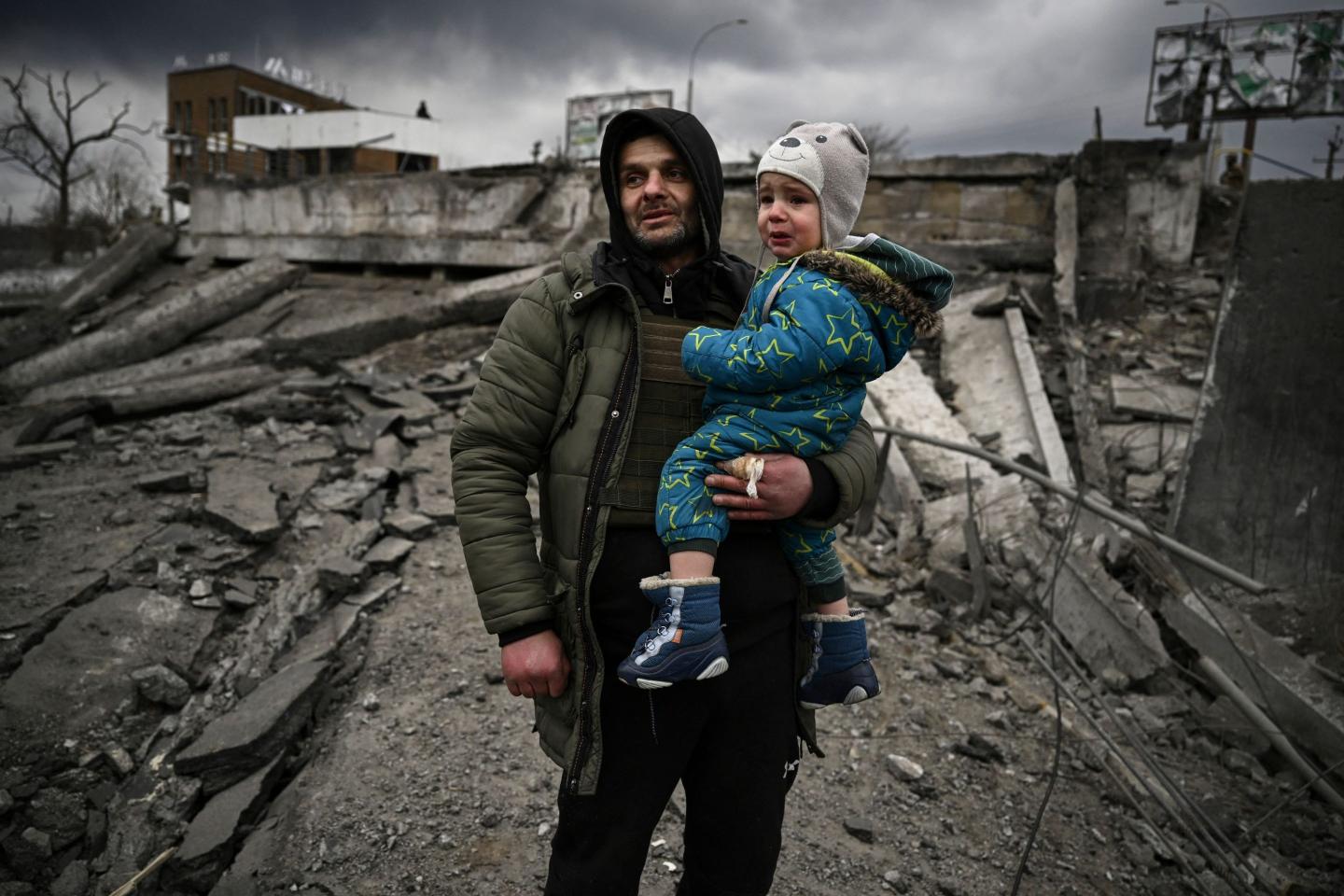 A man holds a crying child in the bombed out city of Irpin, Ukraine.