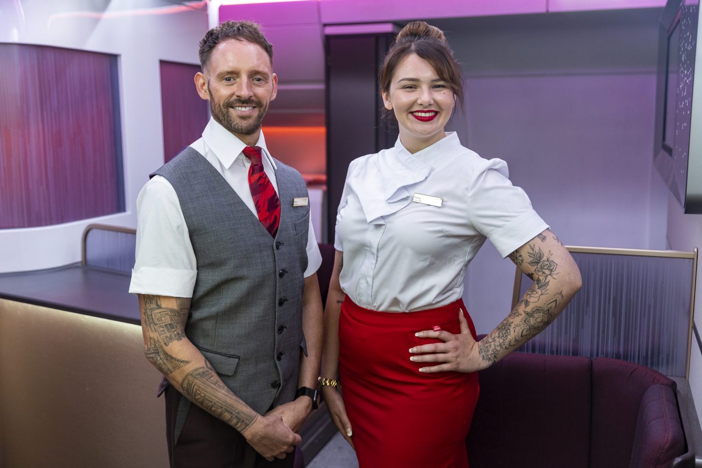 Two uniformed Virgin Atlantic cabin crew members are pictured with their arm tattoos on display.
