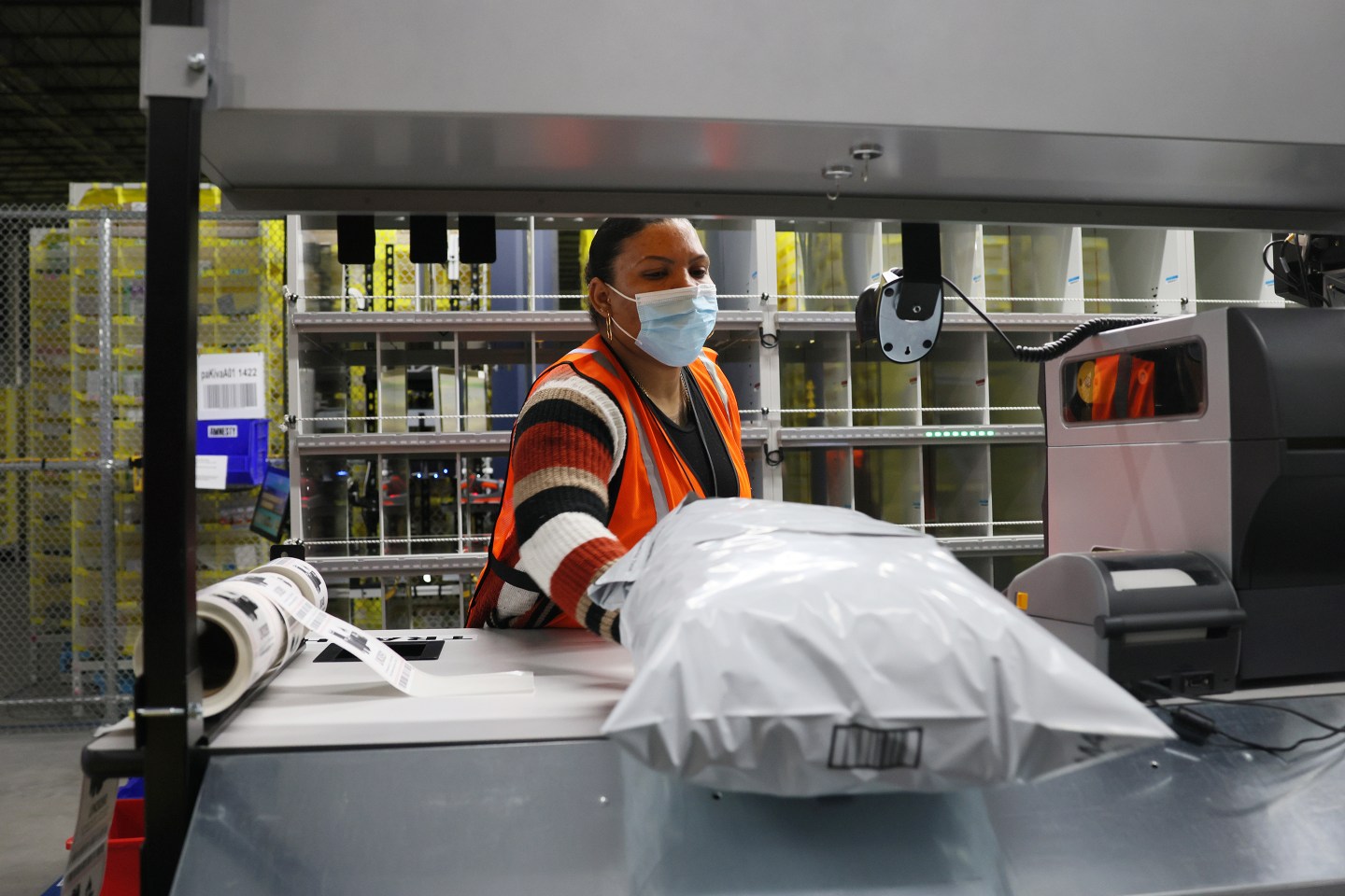 A woman Amazon employee packs items up to be shipped in a warehouse.