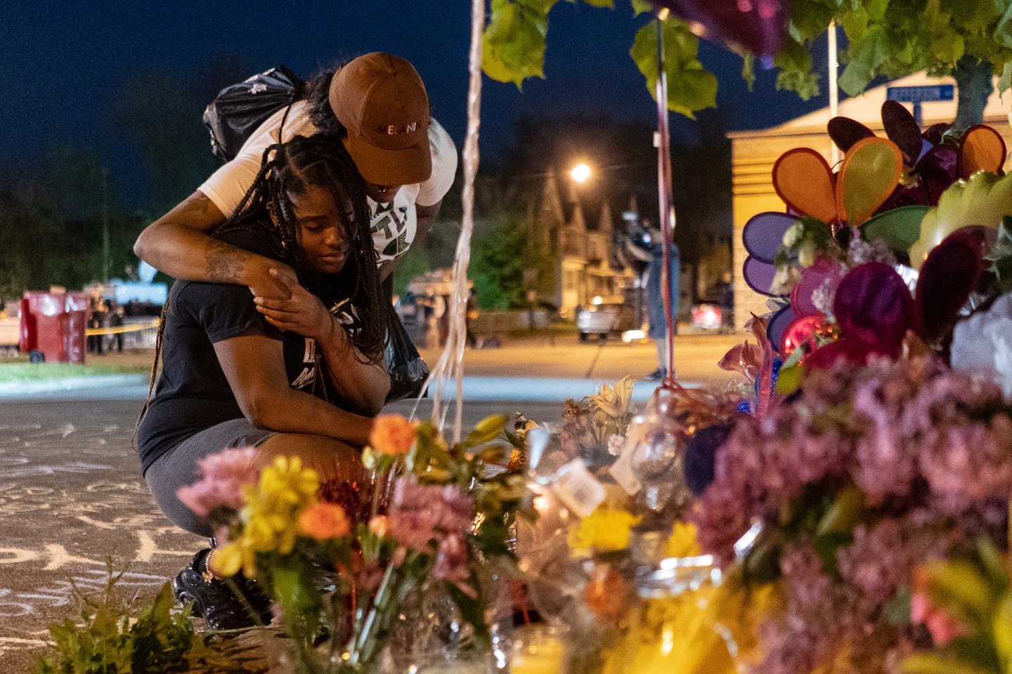 Mourners hug each other at a memorial honoring the victims of the Tops shooting in Buffalo.