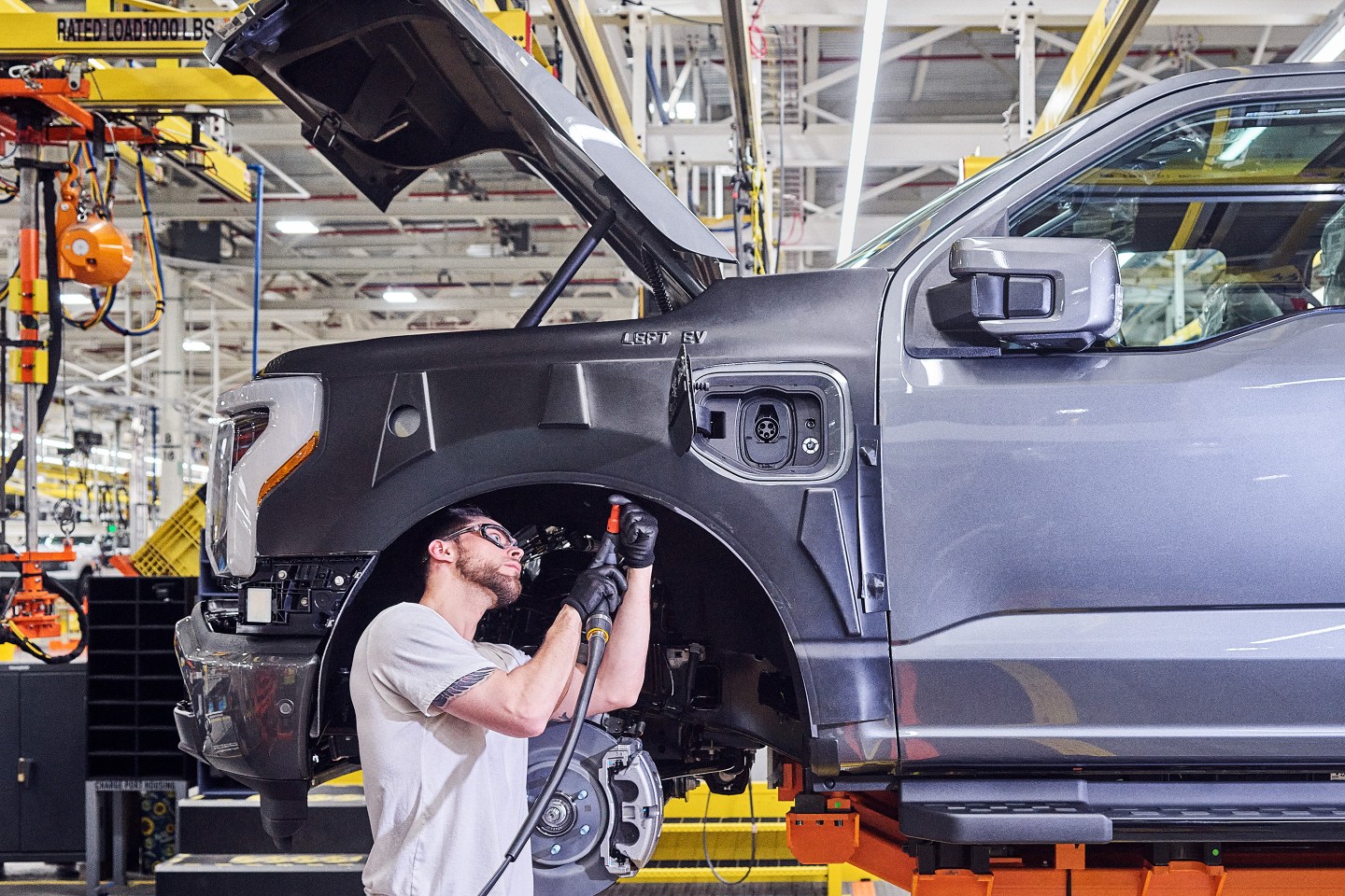 A NEW MODEL T?: A Ford employee works on an F-150 Lightning, the model Ford hopes will woo more U.S. drivers to EVs.