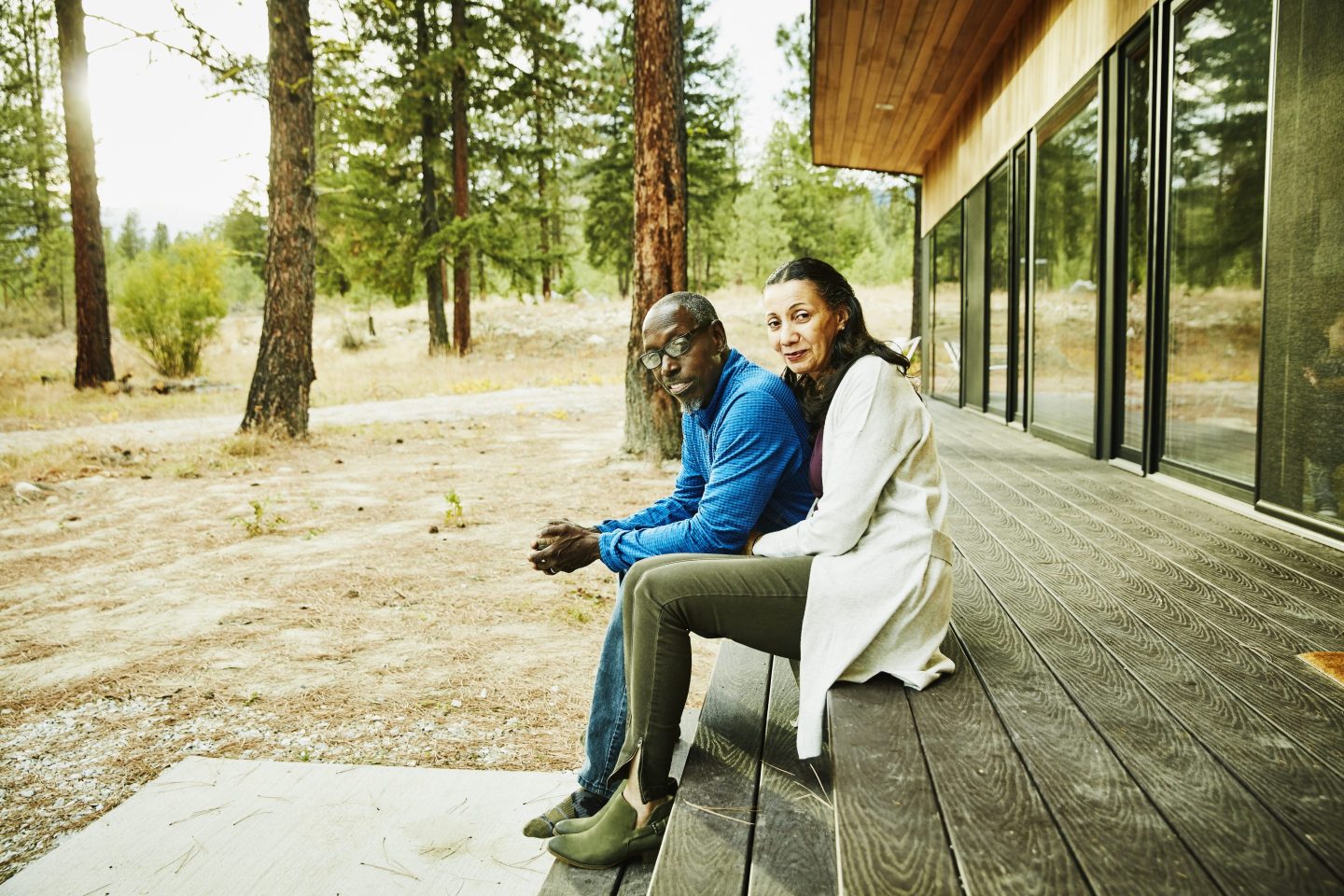 Senior couple sitting together on porch of cabin in woods