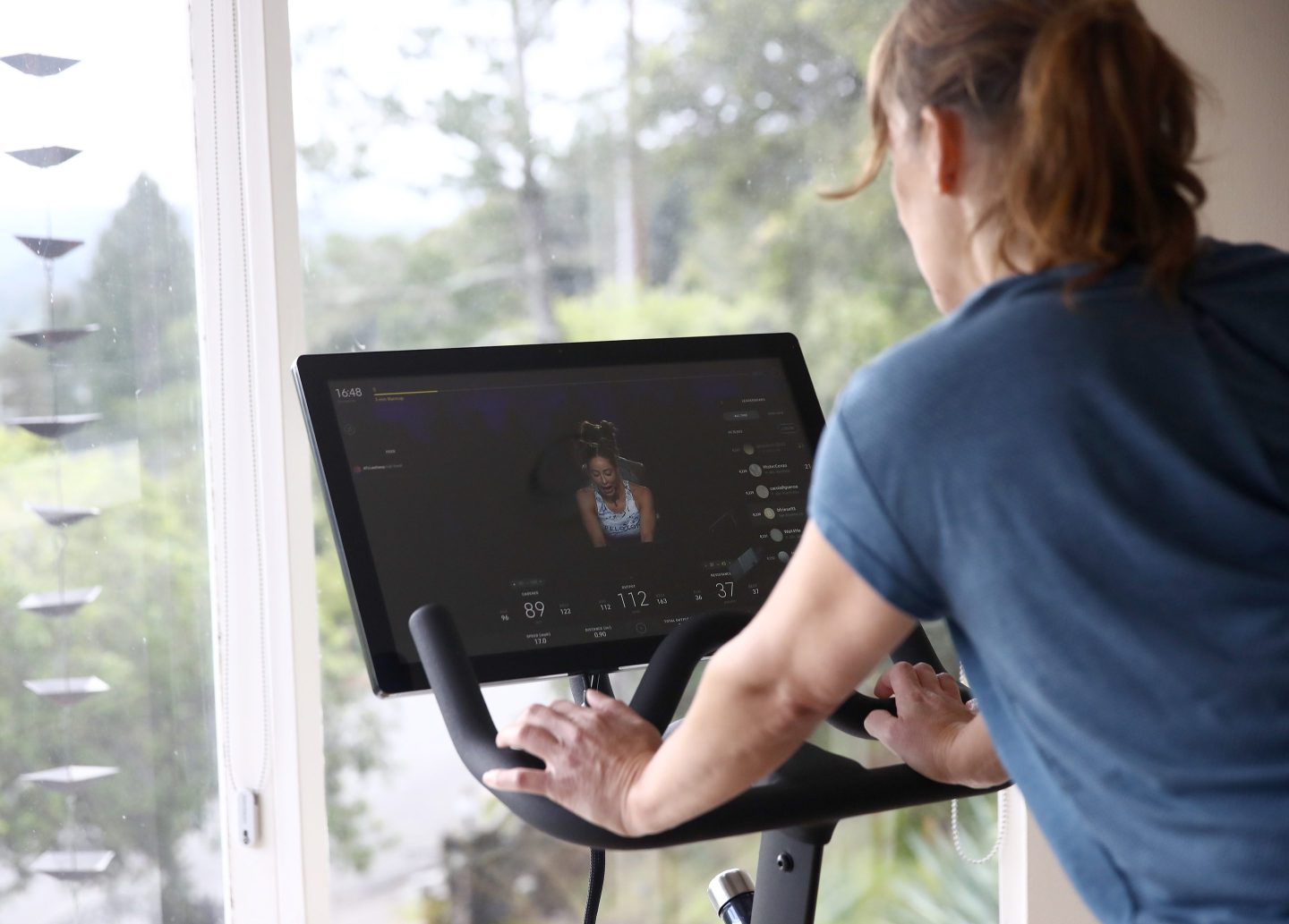 A woman is seen riding her Peloton exercise bike.