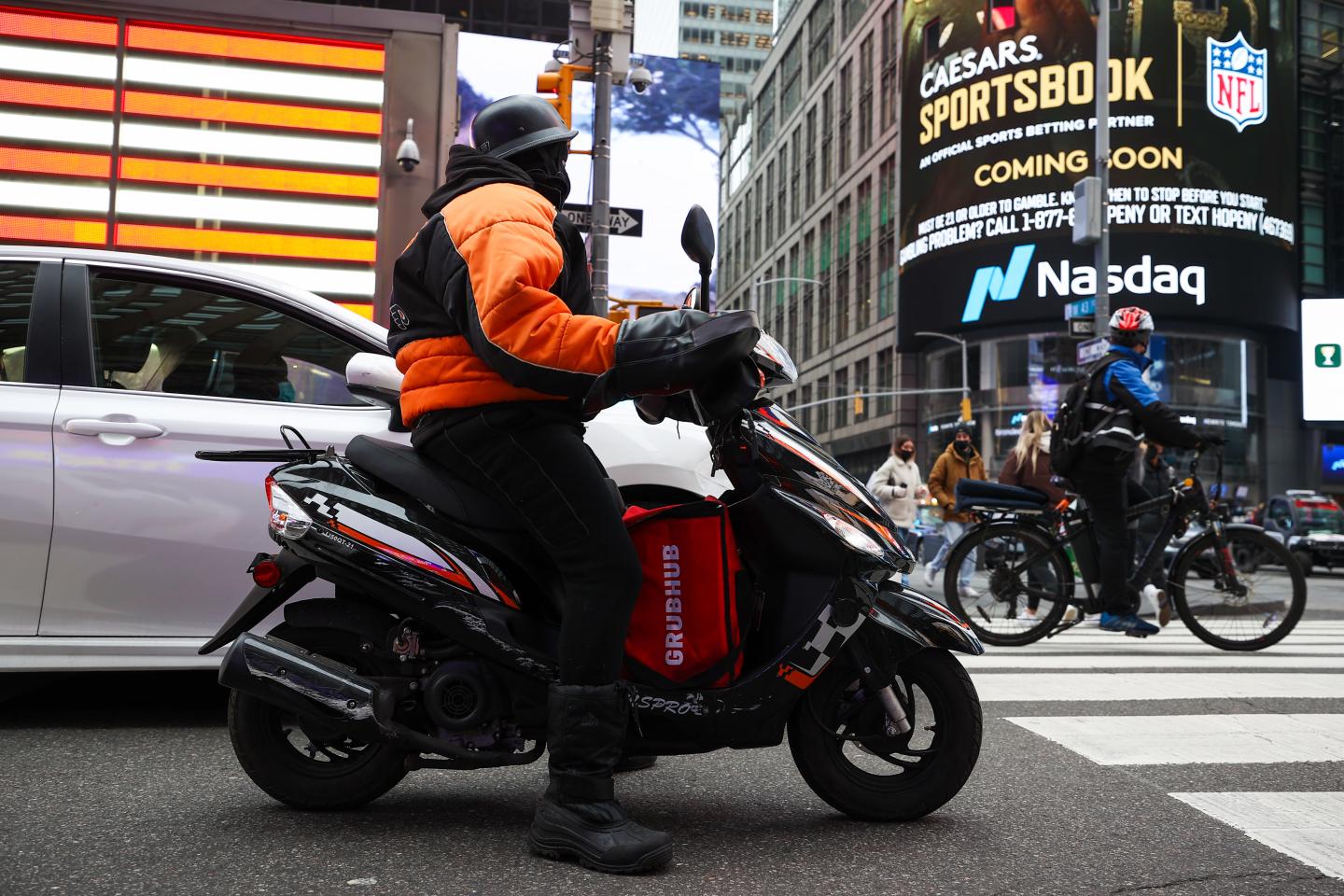 A GrubHub delivery driver on a scooter passes Times Square in New York City on December 29, 2021.