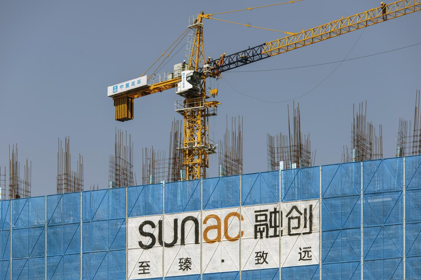 A sign for Sunac hangs from a building under construction