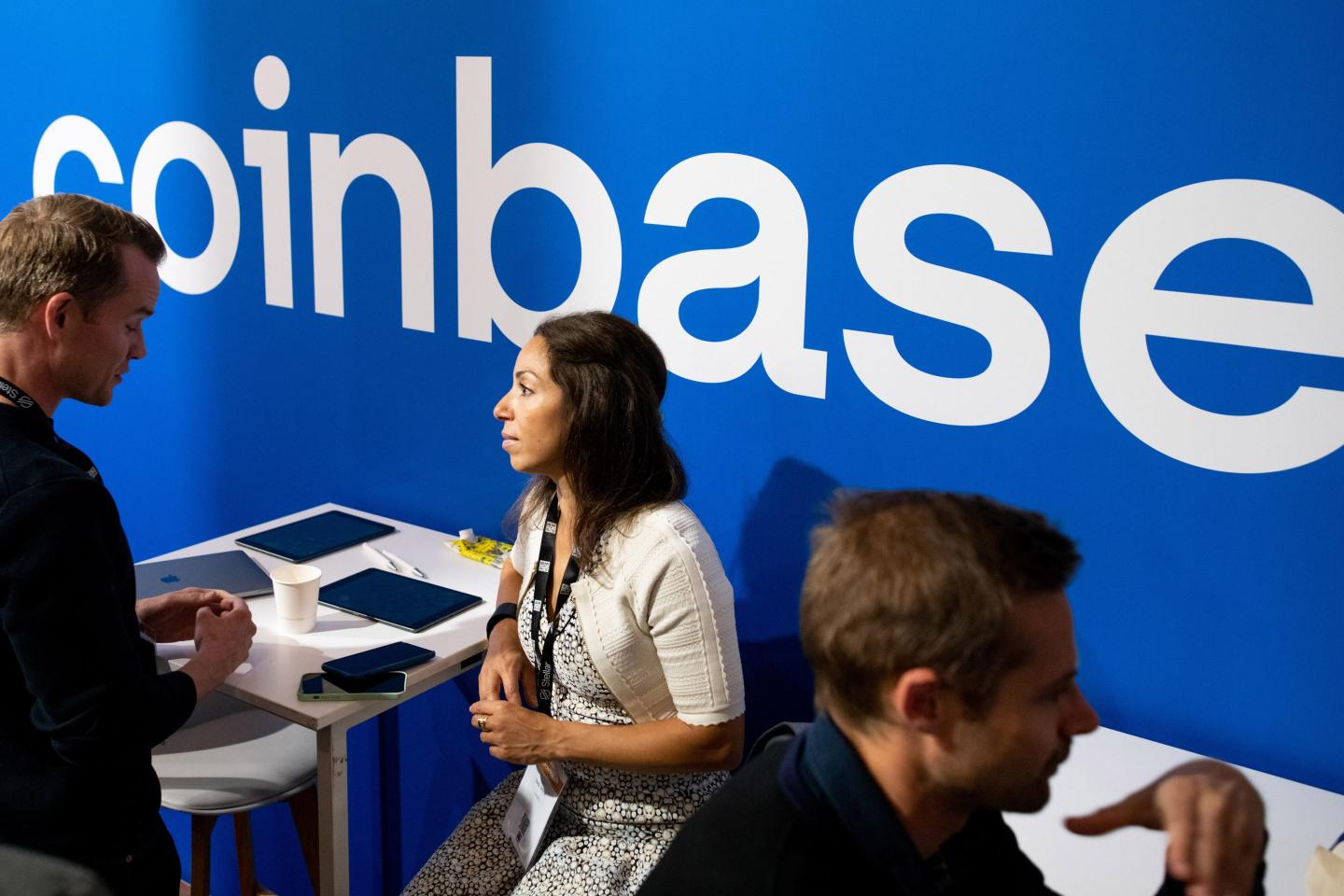 People in front of the Coinbase logo