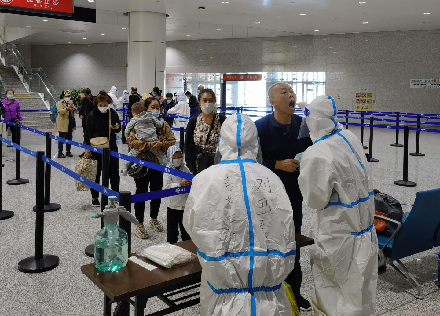 Chinese passengers line up for throat swabs after disembarking a flight.