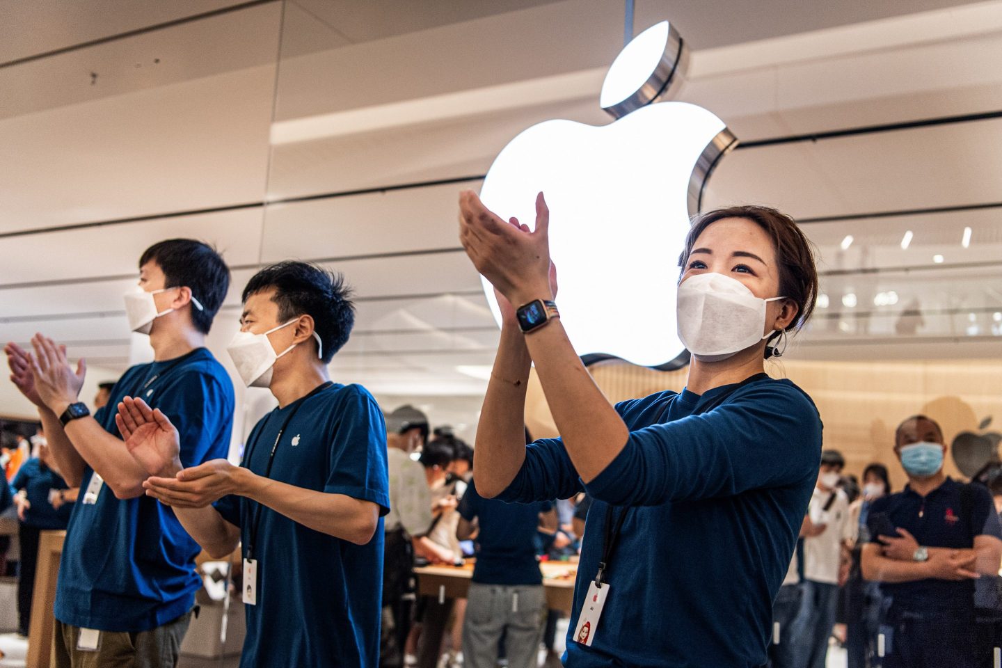 Apple staff wearing masks welcome customers at the opening