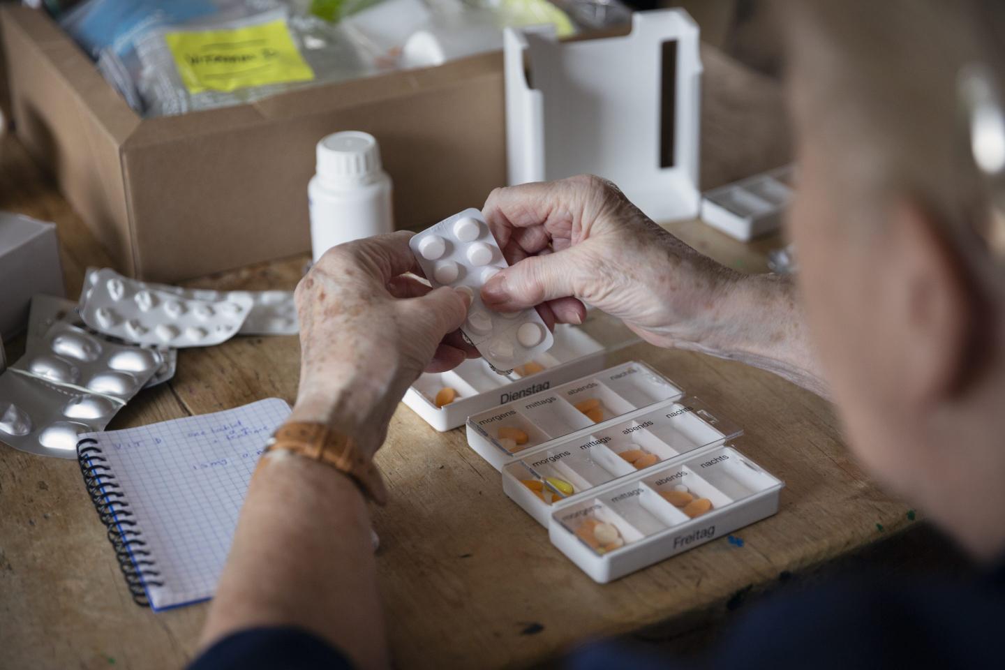 Woman puts pills into a weekly medication dispenser