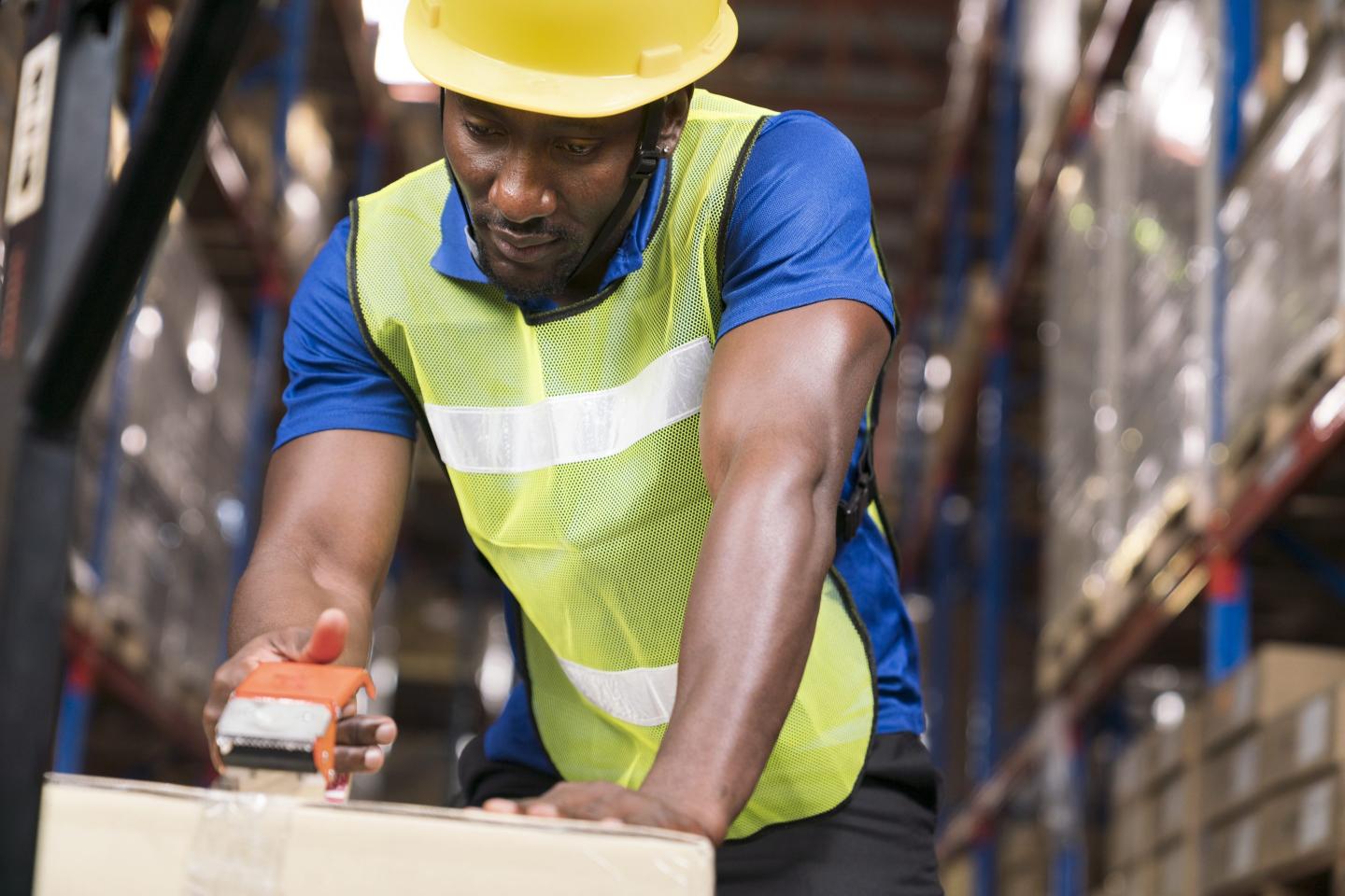younger black worker taping a box