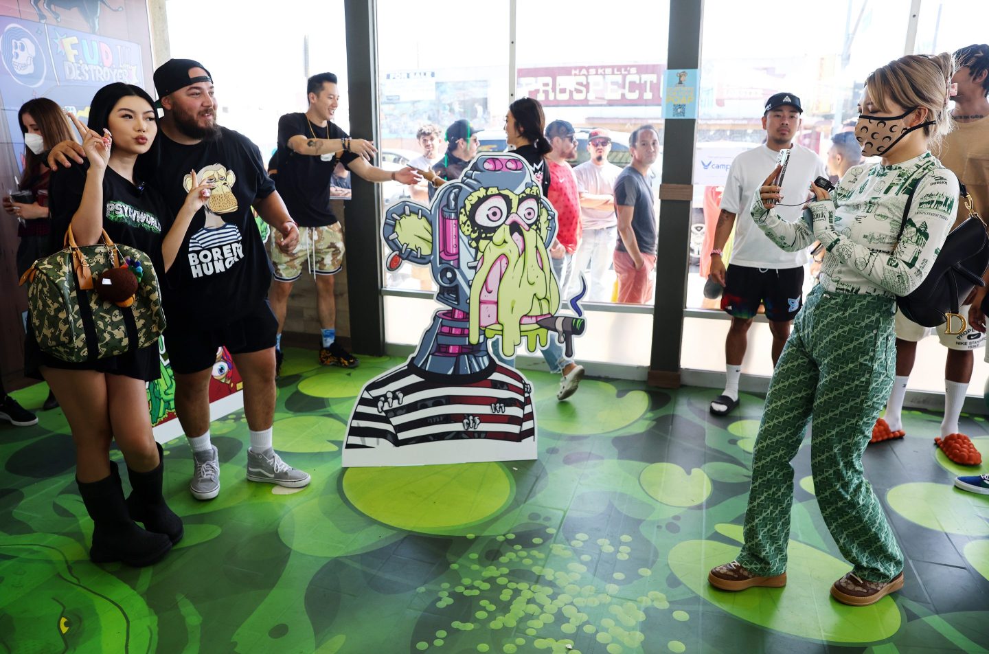 People pose at the opening of a Bored Ape themed pop-up burger shop in LA.