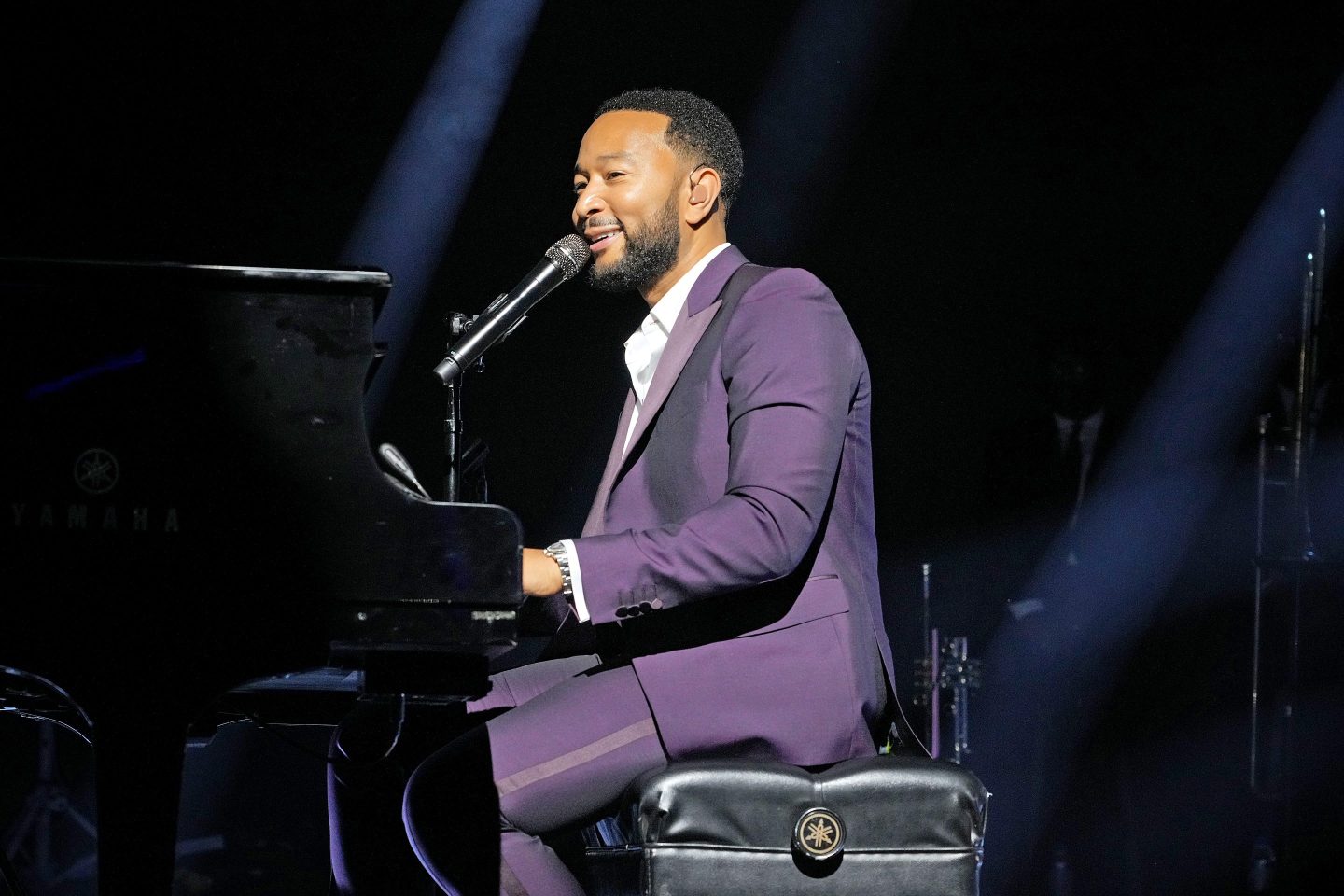 JOhn Legend playing piano and singing into a microphone