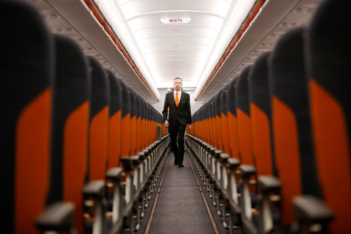 A member of EasyJet's cabin crew is pictured walking down the aisle of an empty plane.