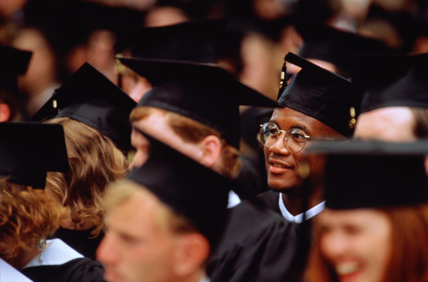 Graduates at graduation ceremony (focus on young man in glasses)