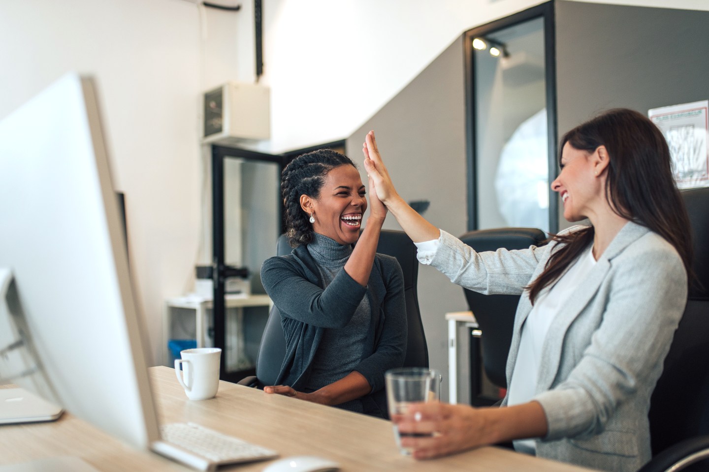 Two women high-fiving at work.