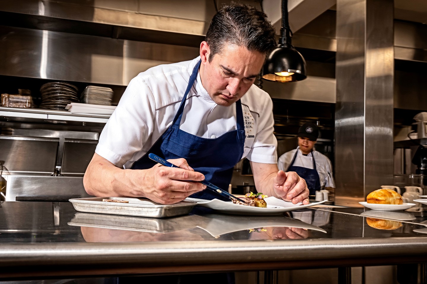 Chef Gregory James plates a dish of dry-aged tuna in the kitchen at The Inn at Perry Cabin.